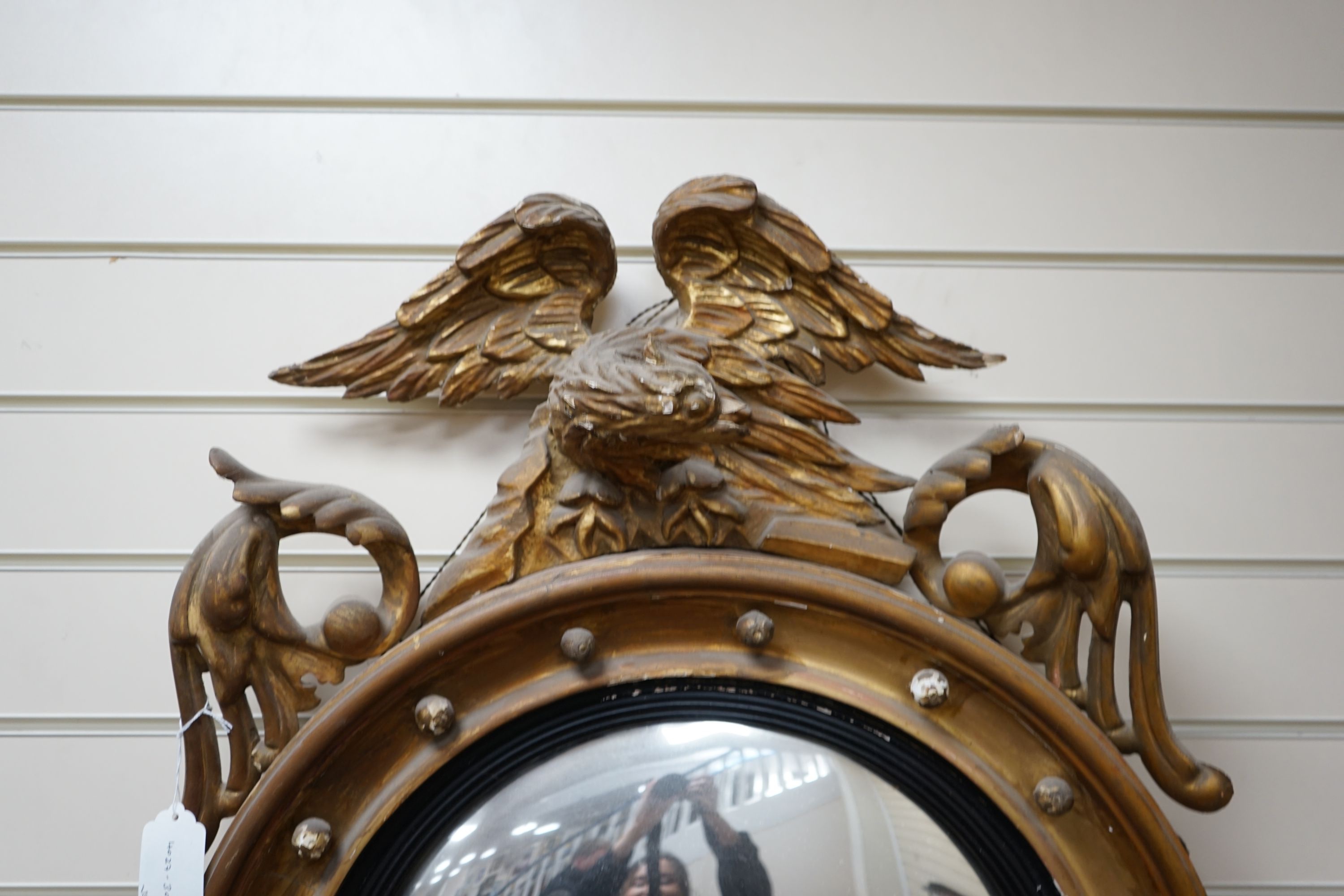 A 19th century gilt and composite circular convex mirror with eagle pediment, width 60cm height 100cm